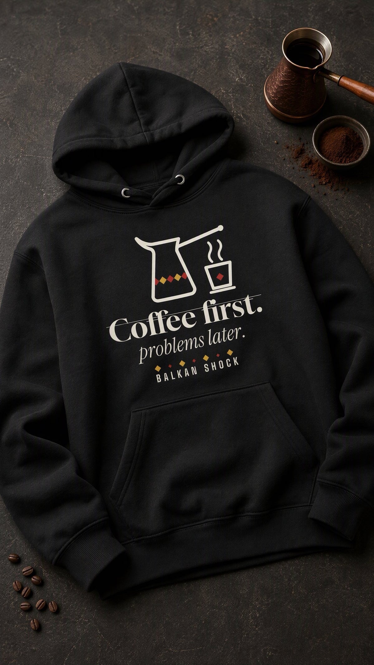Coffee First, Problems Later hoodie laid flat next to a copper džezva and ground coffee